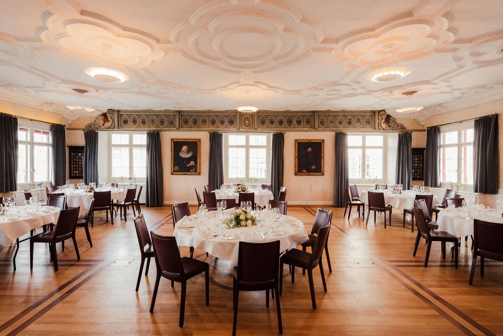 Historischer Saal mit Stuckdecke und festlich gedeckten Rundtischen