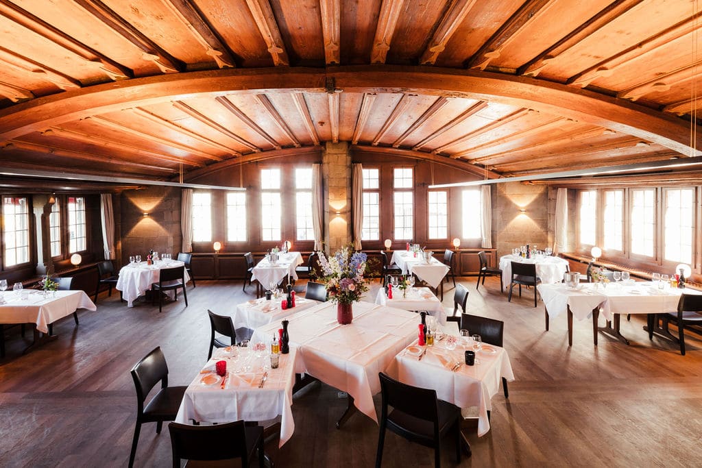 Gotischer Saal im Haus zum Rüden: Kassettendecke aus Holz und festlich gedeckte Rundtische