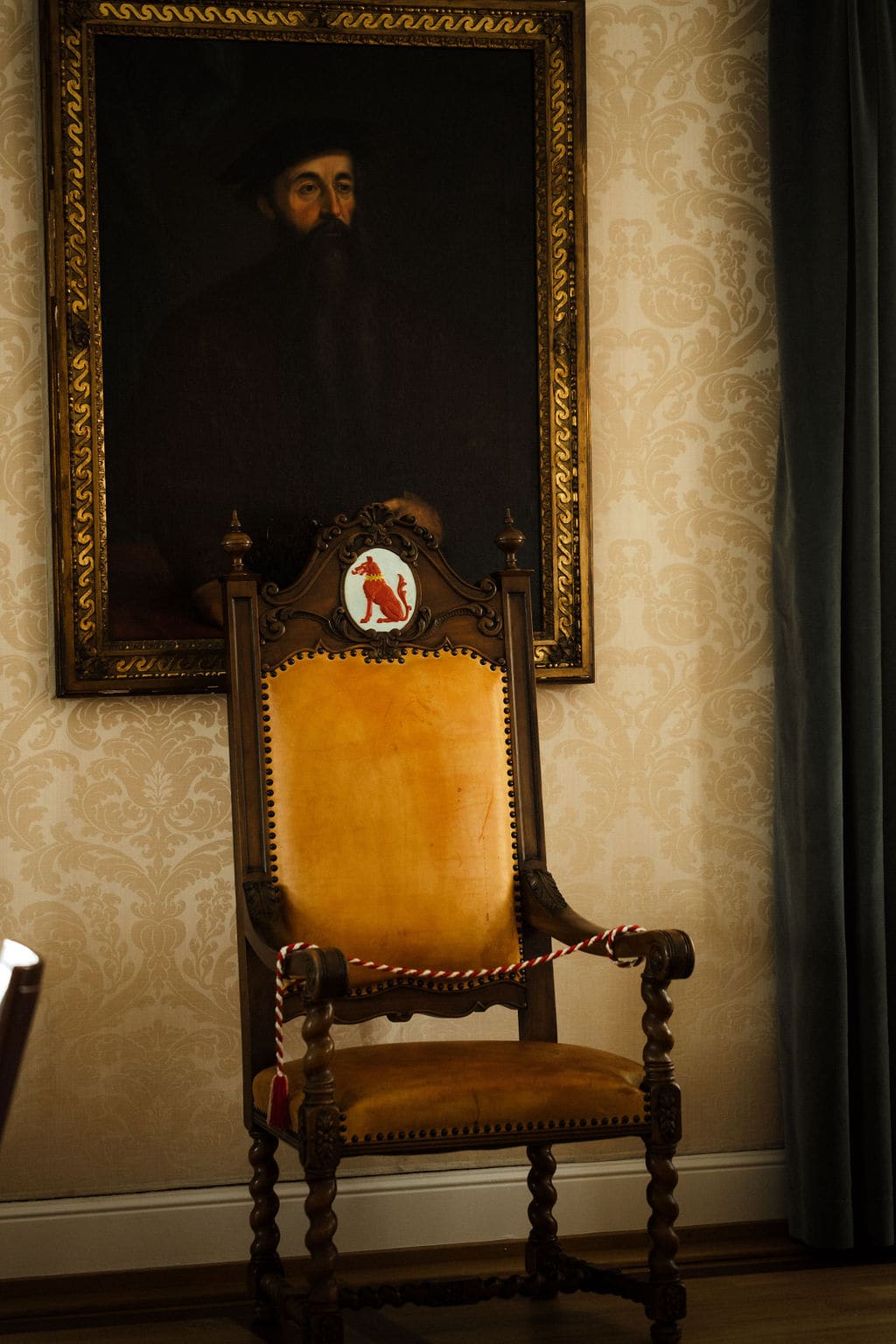 Historischer Stuhl mit Wappen vor gemusterter Wand