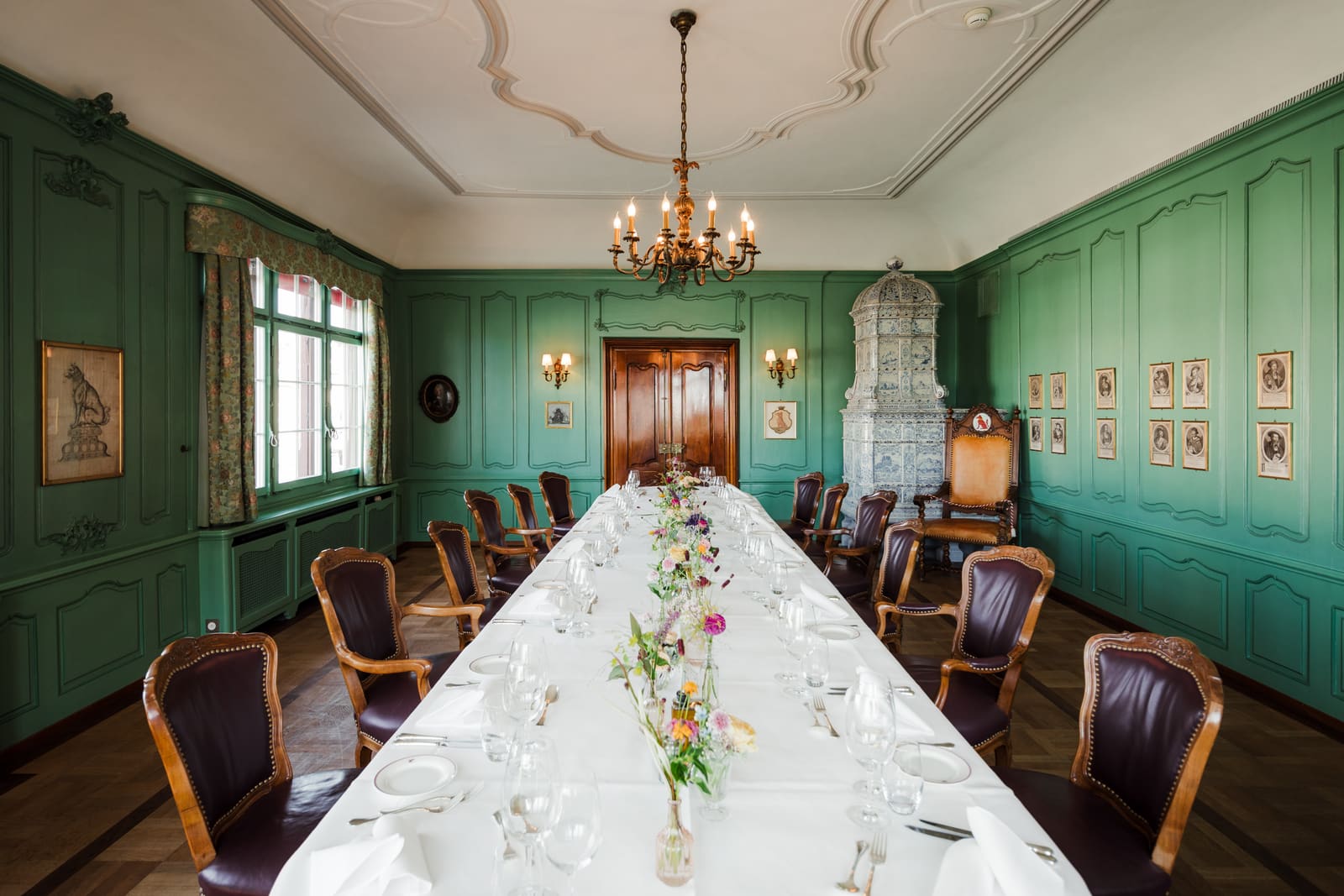 Historisches Zimmer mit grüner Täfelung und langer festlich gedeckter Tafel